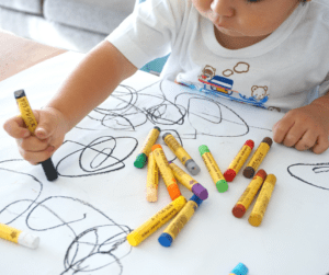 A child colors on paper with crayons
