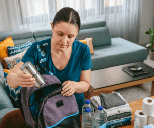 A mom packs water bottles into a purple backpack.