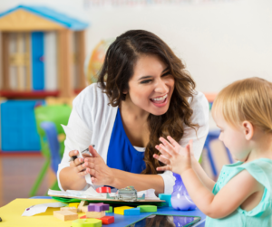 An early intervention therapist works with a child clapping.