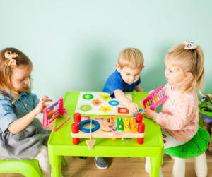 Three toddlers play an early intervention game at a small table.