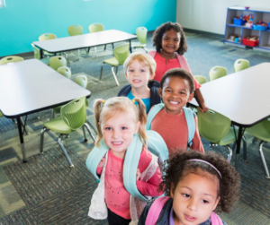 Five young children line up in school classroom.