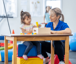 An RBT plays with a young girl at a table