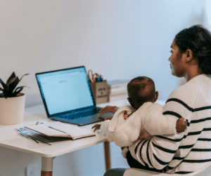 A young mom looks up autism advocate resources on her laptop while holding an infant.